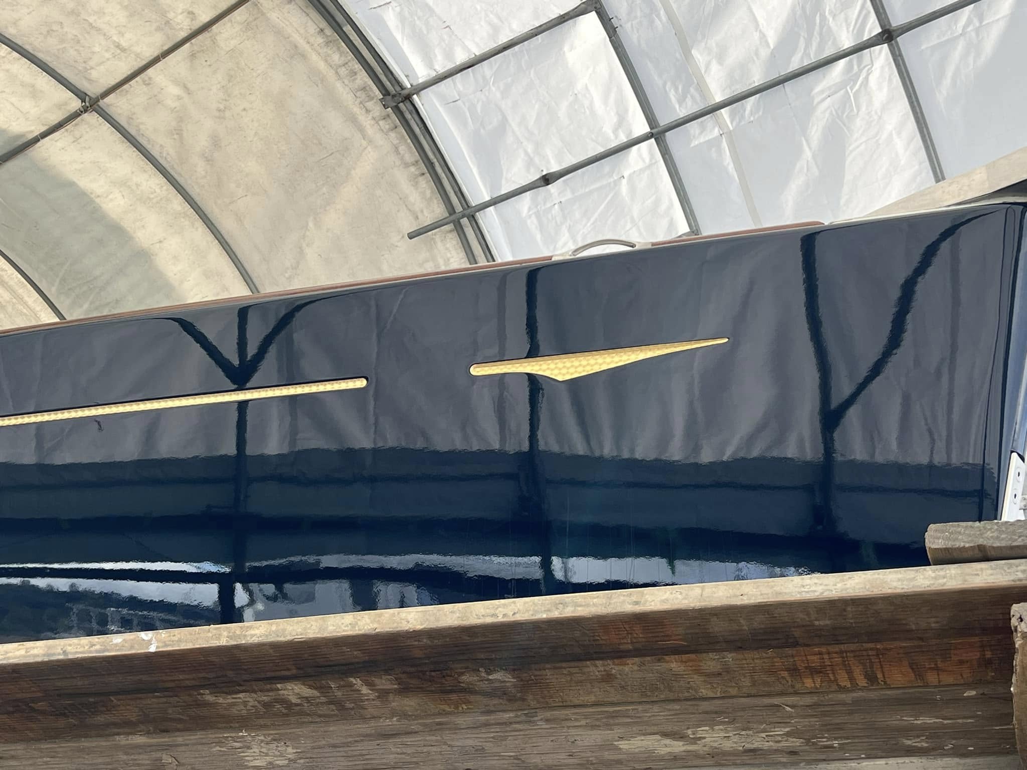 Freshly painted hull with gold cove stripe detail in covered bay