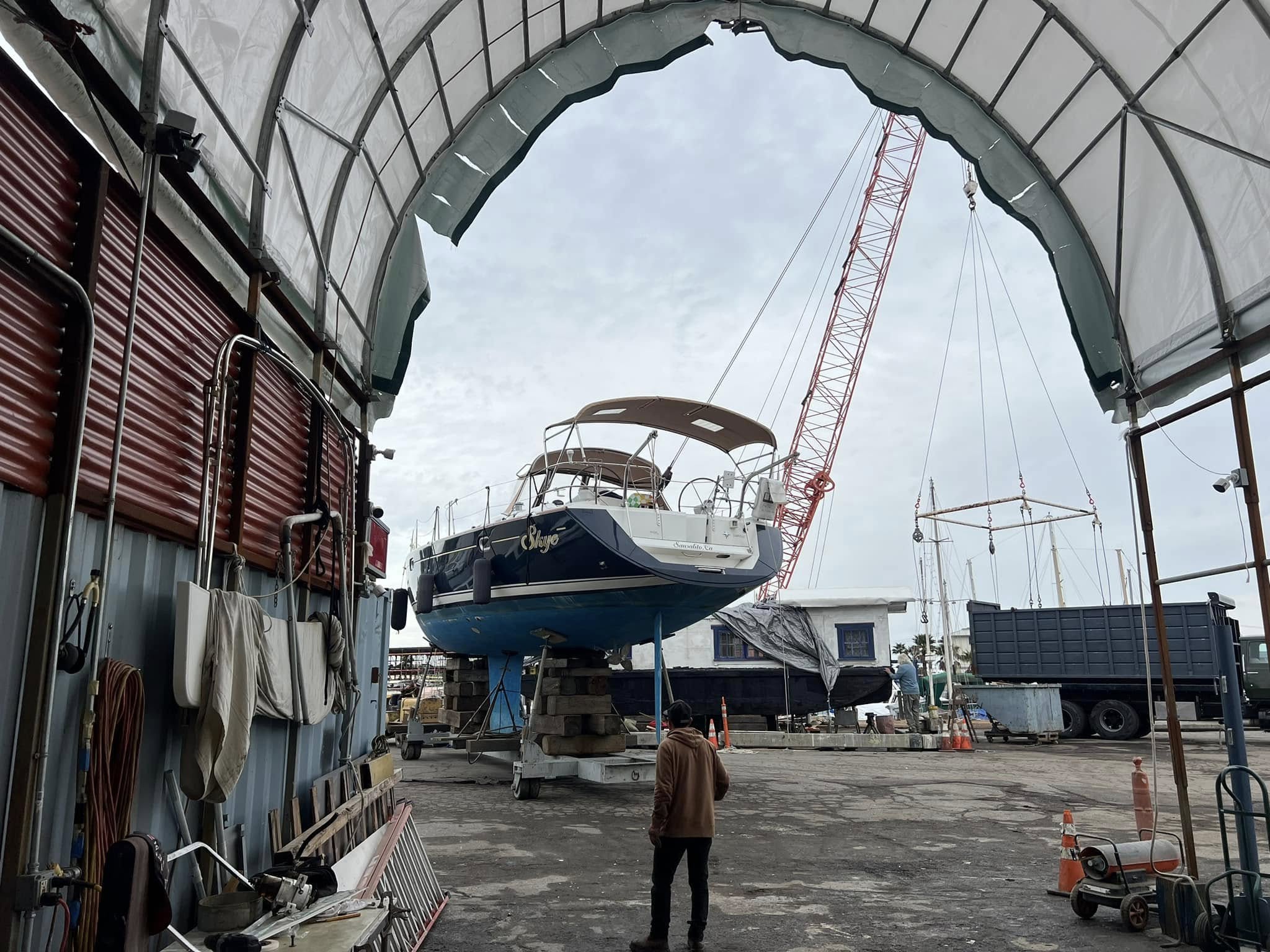 Large sailboat in covered work bay with crane