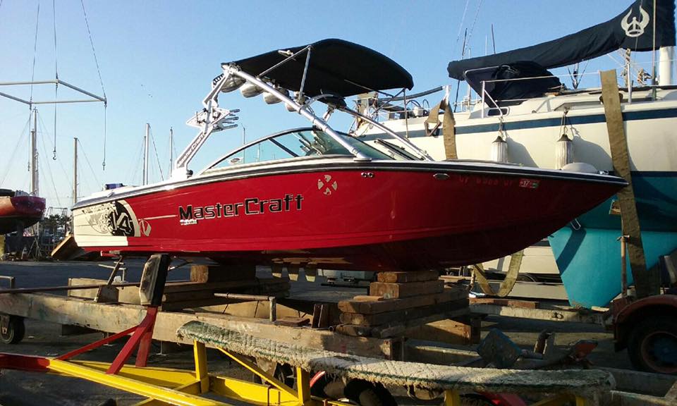 Red MasterCraft X14 wakeboard boat on stands in yard